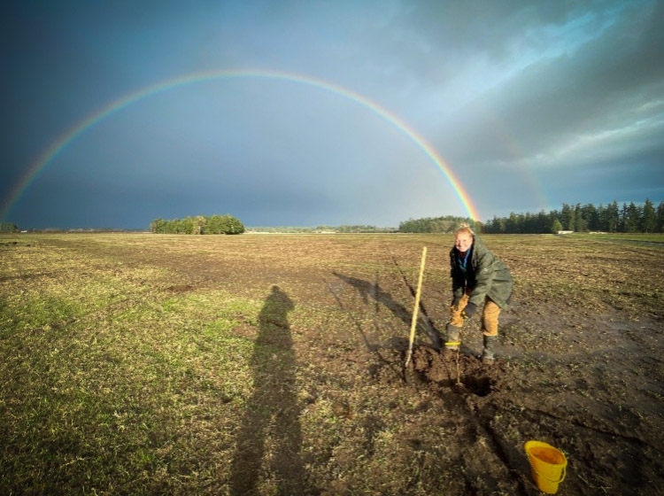 rainbow A view of a grower checking the quality of the soil with a rainbow in the background.